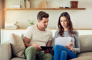 A man and women discussing finances while sitting on the couch.