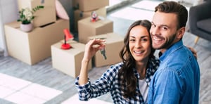 A young couple holds happily a key to their new home