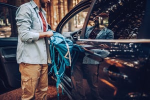 A man removing a tent from his car prior to starting a hike.